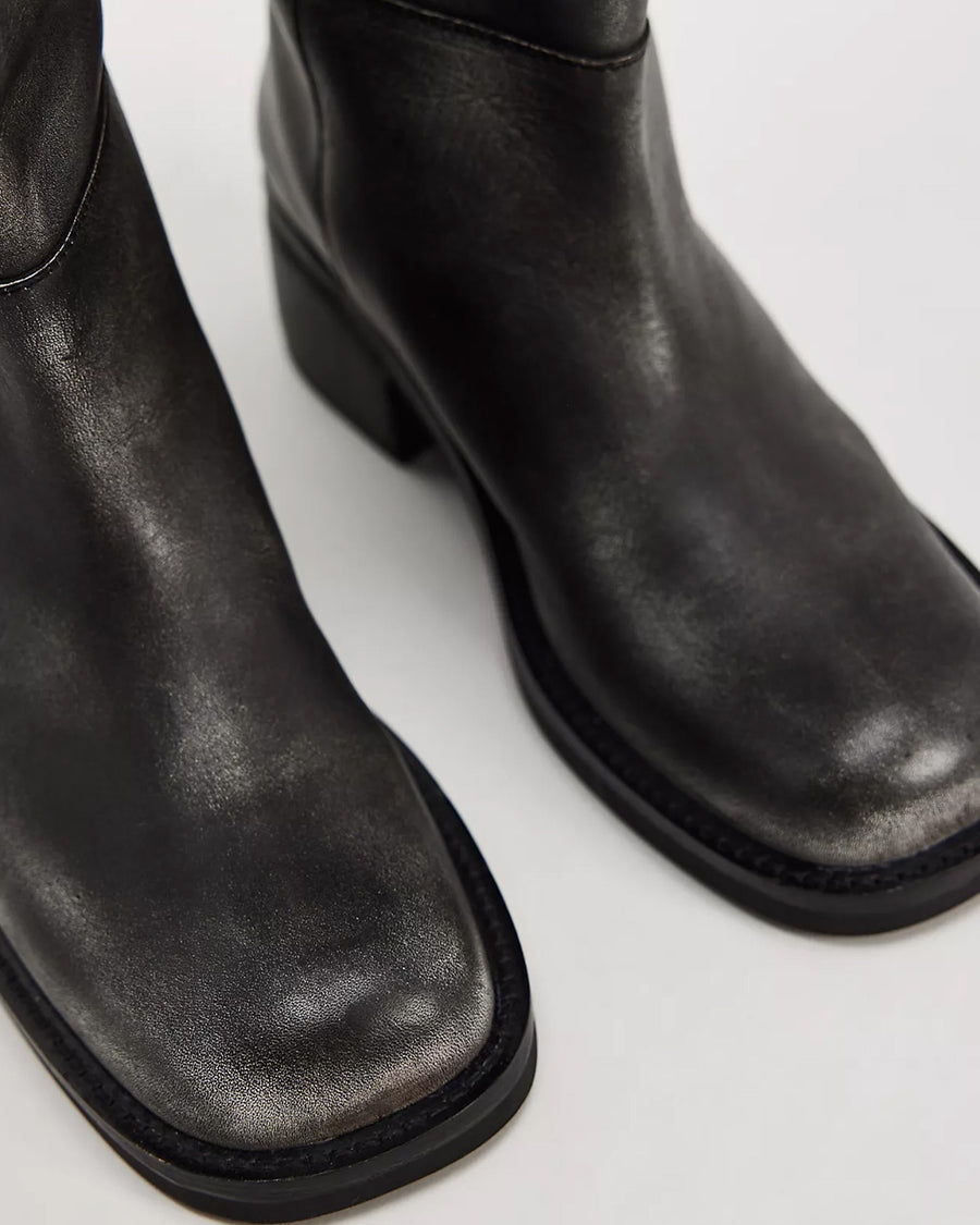 up close of model wearing black distressed leather pull-on tall boots