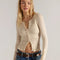 model wearing cream woven cardigan with criss-cross details and ruffles on the hem and sleeves