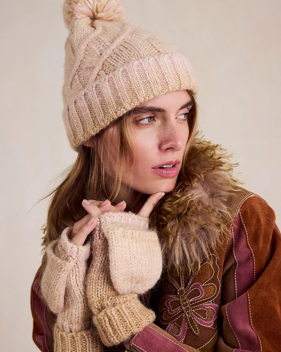 model wearing thick knit ivory winter hat with pom and fingerless gloves/mittens