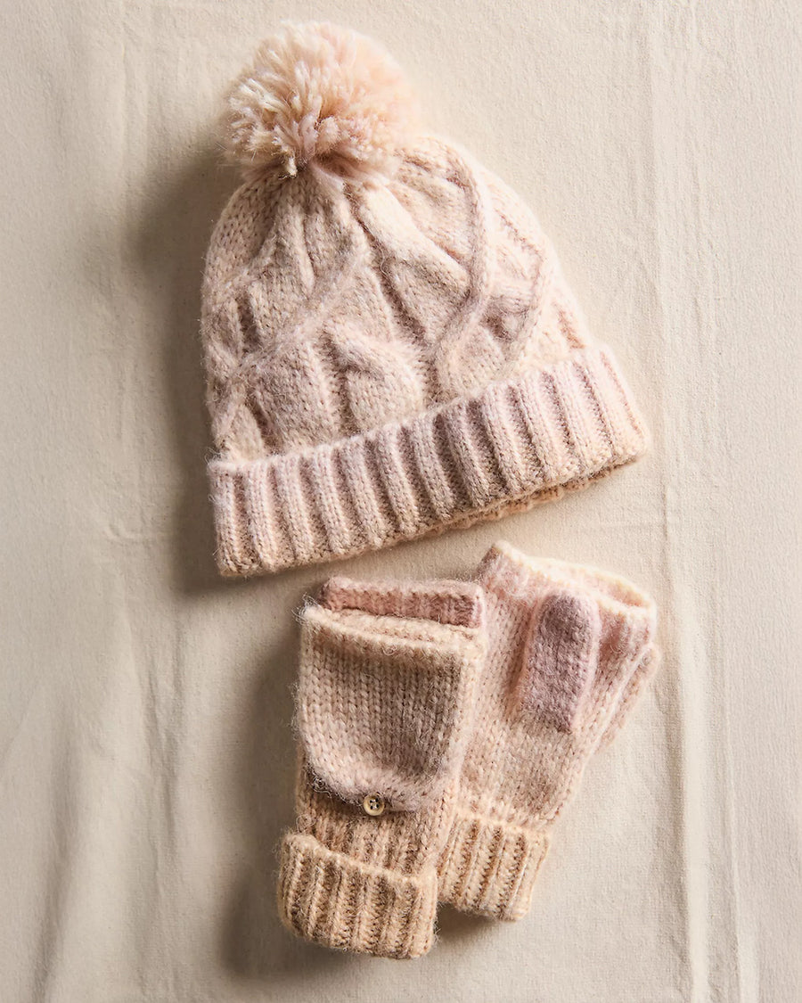 thick knit ivory winter hat with pom and fingerless gloves/mittens on a cream sheet