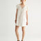 model wearing cream cotton mini dress with crochet scalloped deep v-neckline and cap sleeves