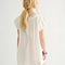 back view of model wearing cream cotton mini dress with crochet scalloped deep v-neckline and cap sleeves