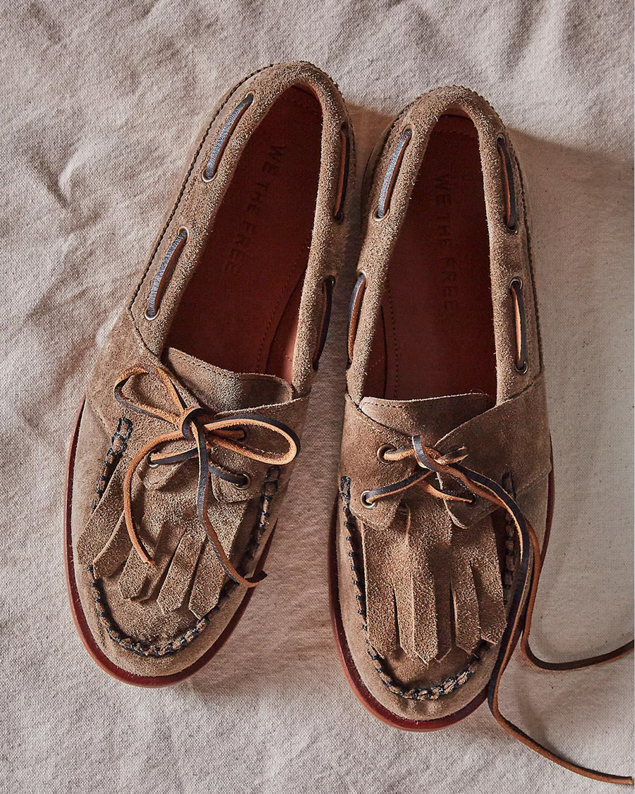 top view of taupe suede slip on boat shoe with tie top and fringe detail