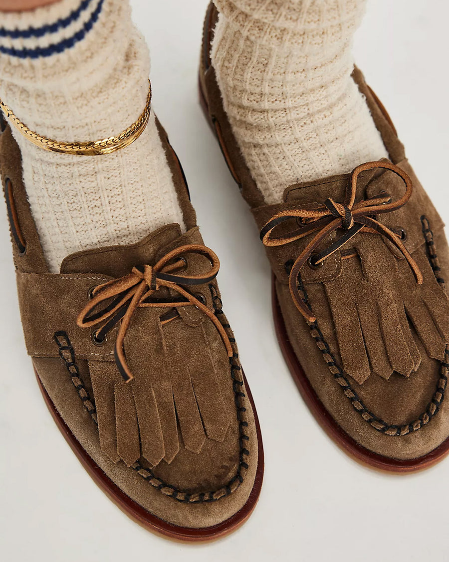 top view of model wearing taupe suede slip on boat shoe with tie top and fringe detail