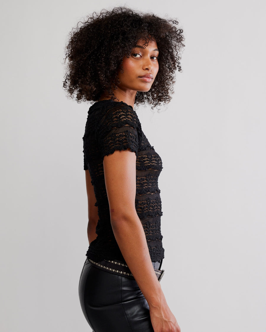 side view of model wearing black lace short sleeve top with leather pants