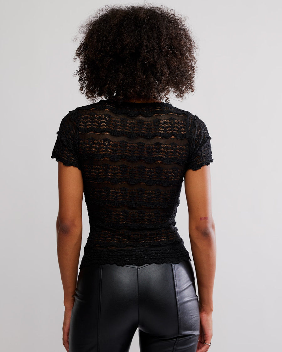 back view of model wearing black lace short sleeve top with leather pants