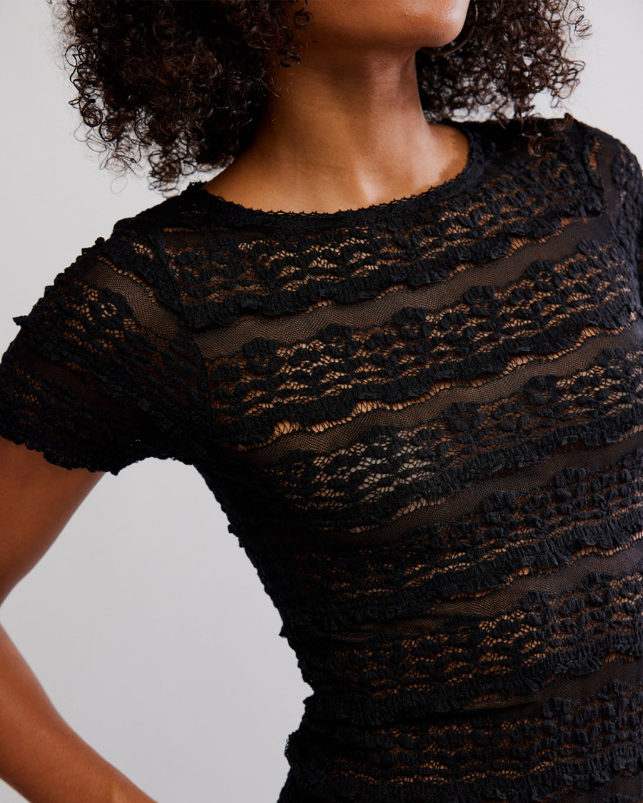 up close of model wearing black lace short sleeve top with leather pants