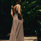 back view of model wearing brown and white stripe maxi dress with deep v neckline and cream tie straps