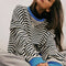 model wearing black and white horizontal stripe crewneck sweatshirt with royal blue trim