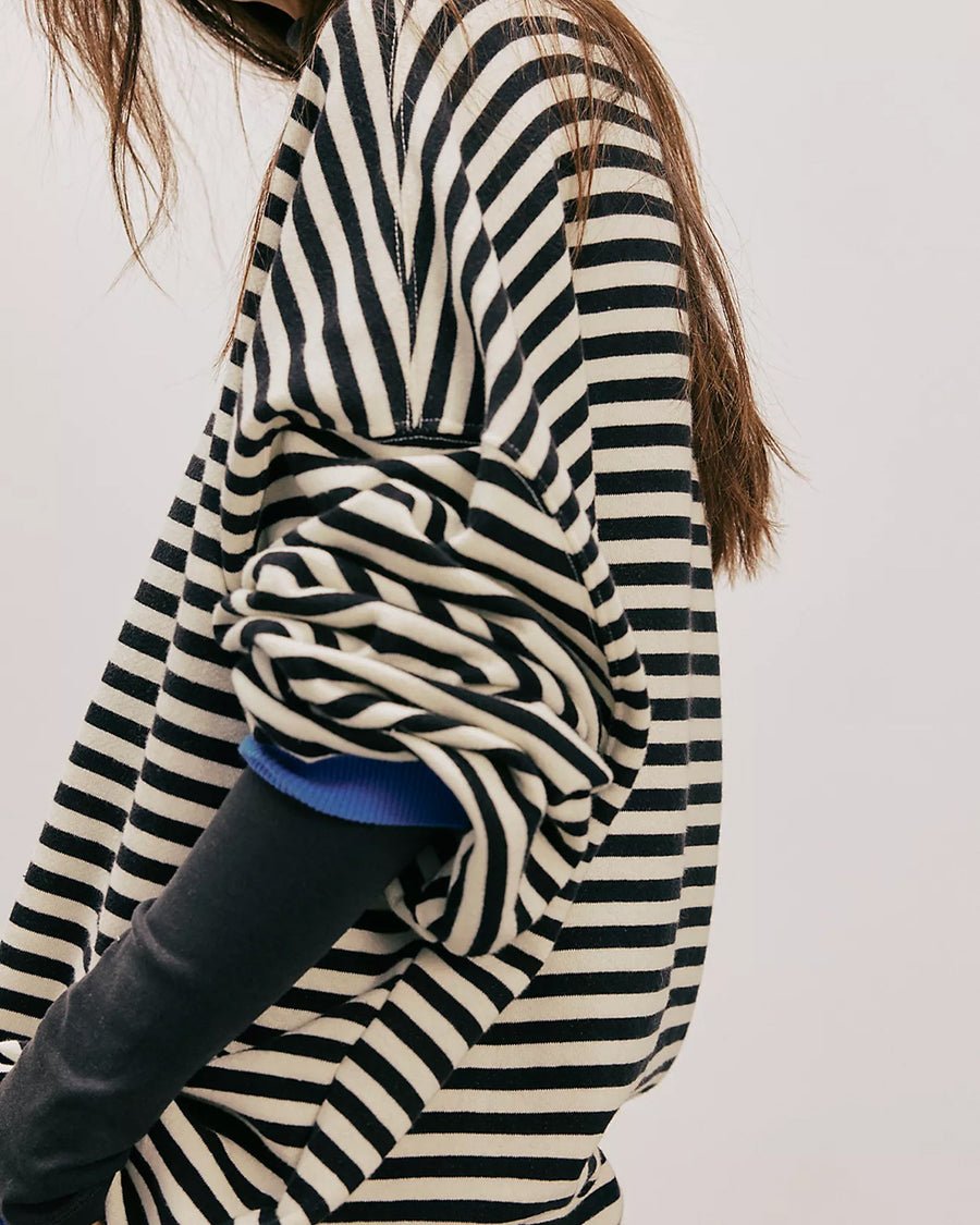 side view of model wearing black and white horizontal stripe crewneck sweatshirt with royal blue trim