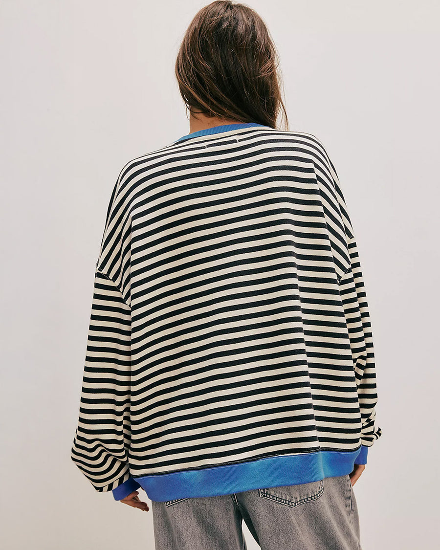 back view of model wearing black and white horizontal stripe crewneck sweatshirt with royal blue trim