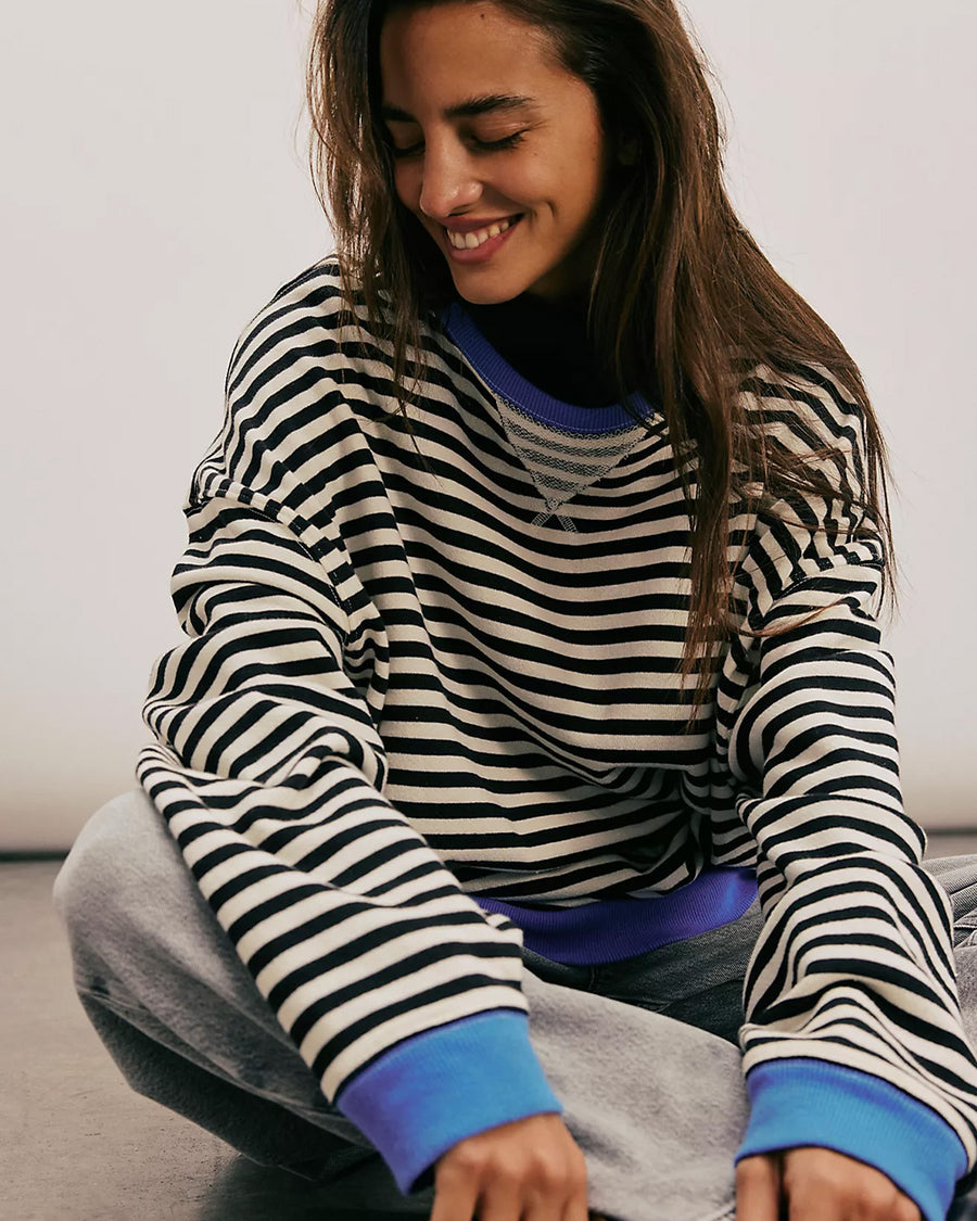 model wearing black and white horizontal stripe crewneck sweatshirt with royal blue trim