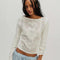 model wearing ivory long sleeve top with floral lace front and back and lace trim on the hems of the sleeves
