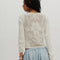 back view of model wearing ivory long sleeve top with floral lace front and back and lace trim on the hems of the sleeves