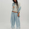 model wearing ivory long sleeve top with floral lace front and back and lace trim on the hems of the sleeves and blue balloon pants