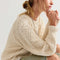 side view of model wearing ivory chunky sweater with blue jeans with holes in the knees