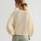 back view of model wearing ivory chunky sweater and blue jeans