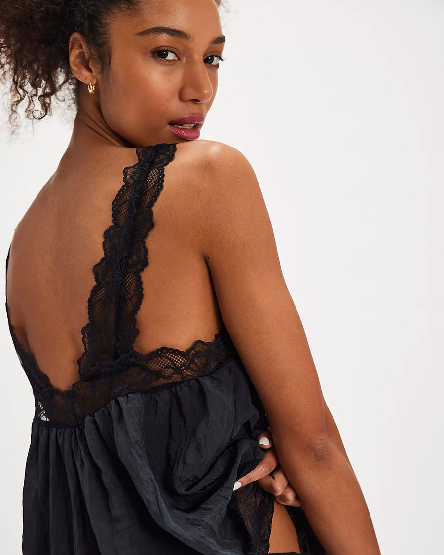 back view of model wearing black silky tank with black lace trim on the bust, straps and hem