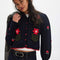 model wearing black cropped cardigan with red folk floral print on the front and sleeves