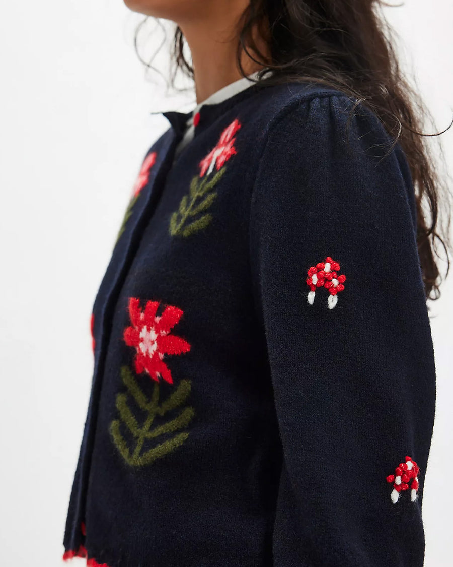 side view of model wearing black cropped cardigan with red folk floral print on the front and sleeves