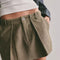 up close of model wearing olive green mini skirt with pleated front and raw hem