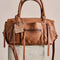 brown leather barrel purse with long strap zipper pulls and various zipper compartments