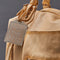 up close of light tan leather purse with several zippered pockets, double handles and crossbody strap