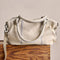 back view of mini washed beige leather purse with several zippered pockets, double handles and crossbody strap