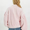 back view of model wearing baby pink cardigan with extended placket, patch pockets and large button front