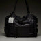 black leather purse with several zippered pockets, double handles and crossbody strap