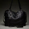 back view of black leather purse with several zippered pockets, double handles and crossbody strap