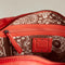 inside of rusty red leather purse with several zippered pockets, double handles and crossbody strap