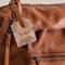 up close of dark brown leather tote bag with several pockets and zippers