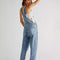 back view of model wearing powder blue denim relaxed fit overalls
