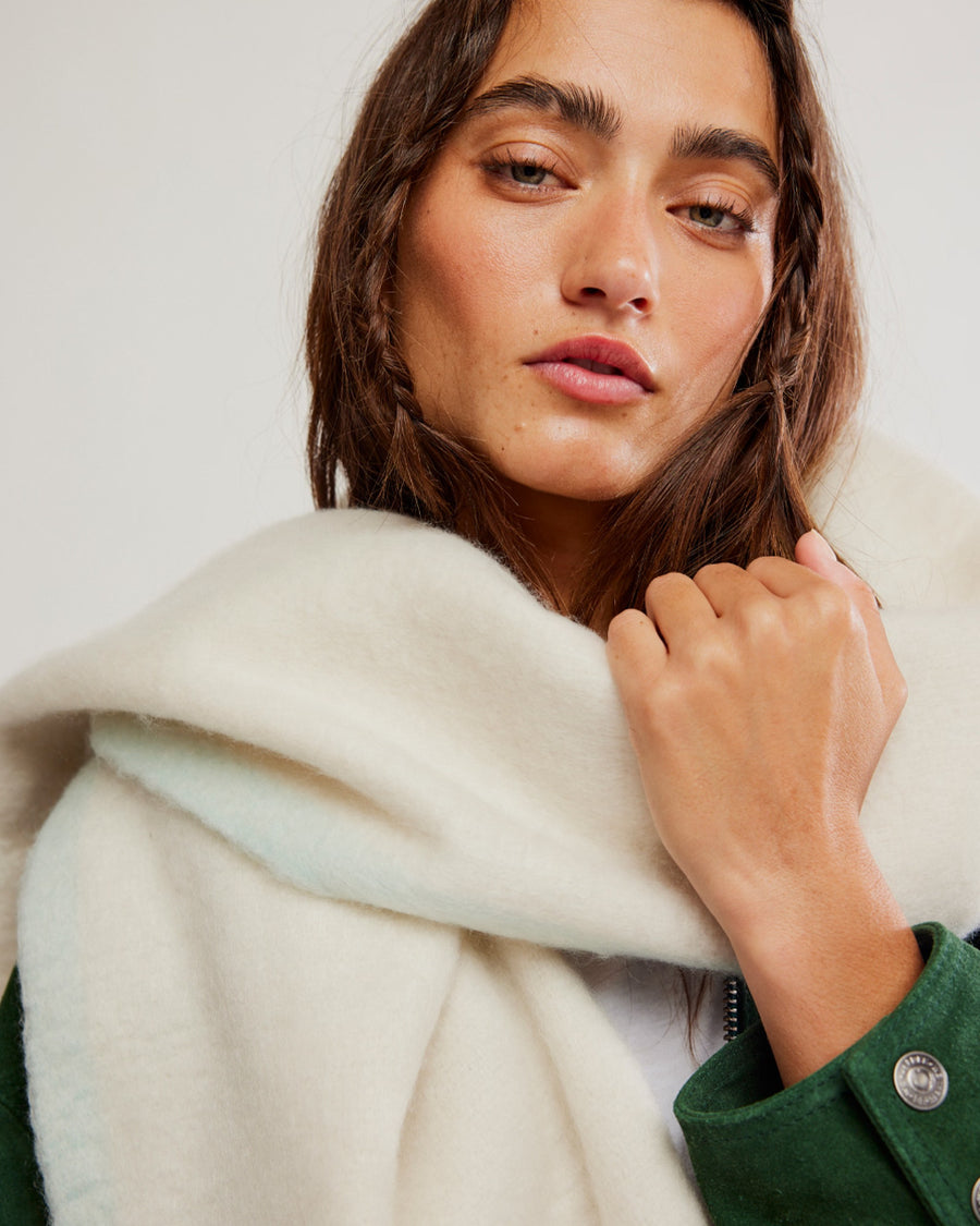 up close of model wearing thick subtle blue and white oversized scarf with white fringe