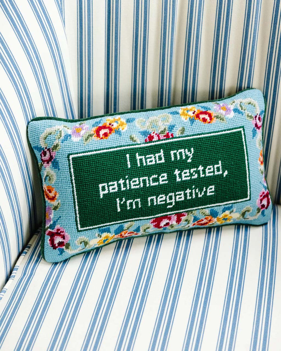 blue floral rectangular throw pillow with 'i had my patience tested, i'm negative' across the front on couch