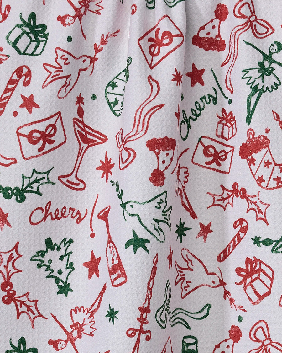 up close of white tea towel with red and green holiday doodle print