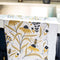 white tea towel with goldenrod floral and bee print folded on a sink