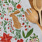 up close of white tea towel with all over poinsettia, deer, rabbit, and fox print