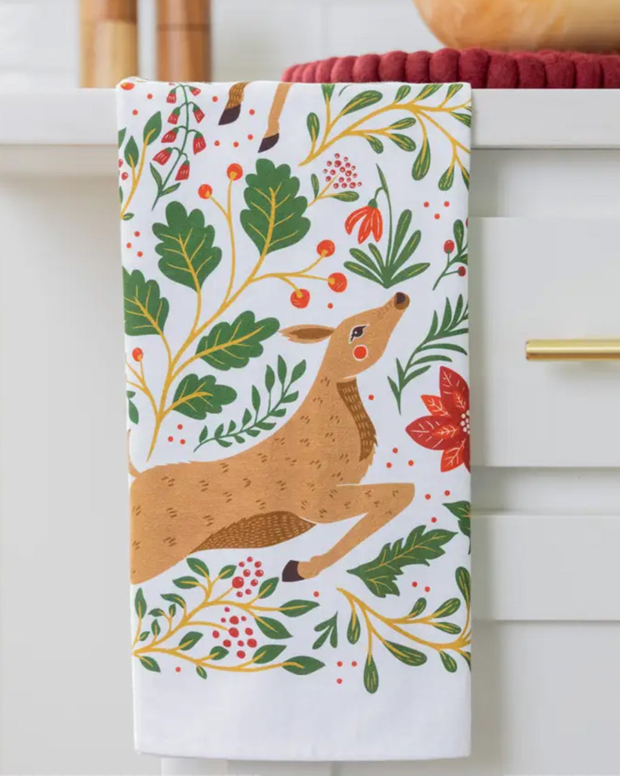 folded white tea towel with all over poinsettia, deer, rabbit, and fox print
