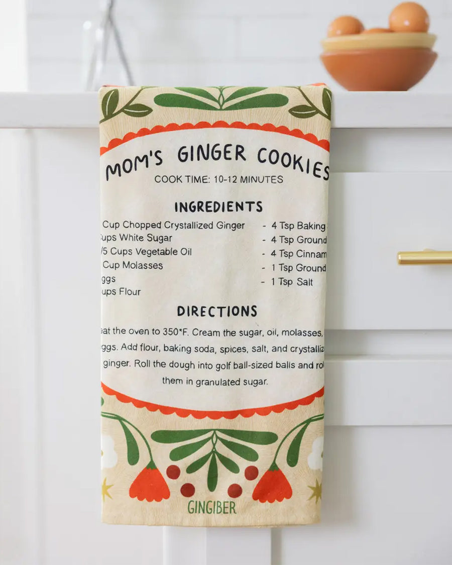 cream tea towel with mom's ginger cookies recipe and surrounded by cardinals and floral print on a counter