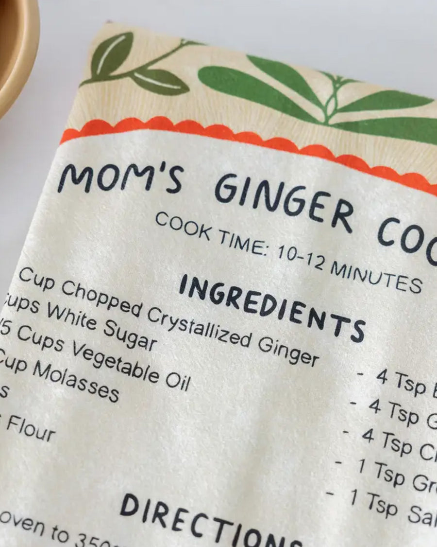 up close of cream tea towel with mom's ginger cookies recipe and surrounded by cardinals and floral print