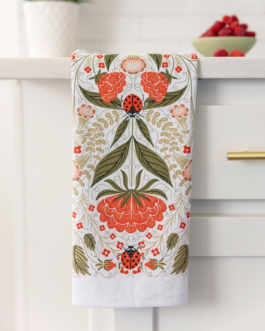folded ladybug and red floral abstract tea towel on a counter