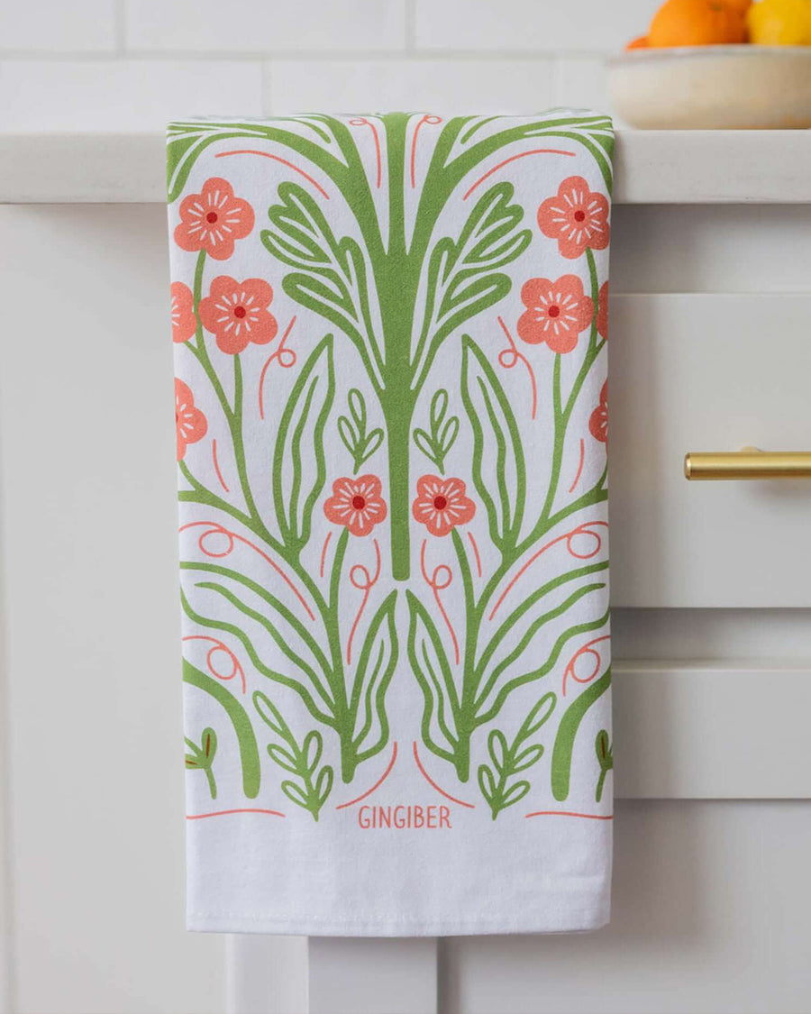folded white tea towel with abstract pink poppy print and greenery