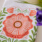 top view of white tea towel with abstract pink poppy print and greenery