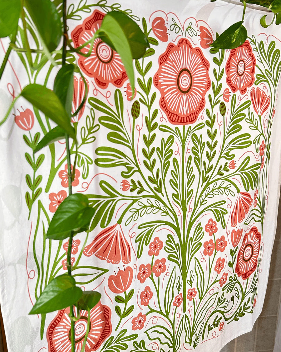 side view of white tea towel with abstract pink poppy print and greenery