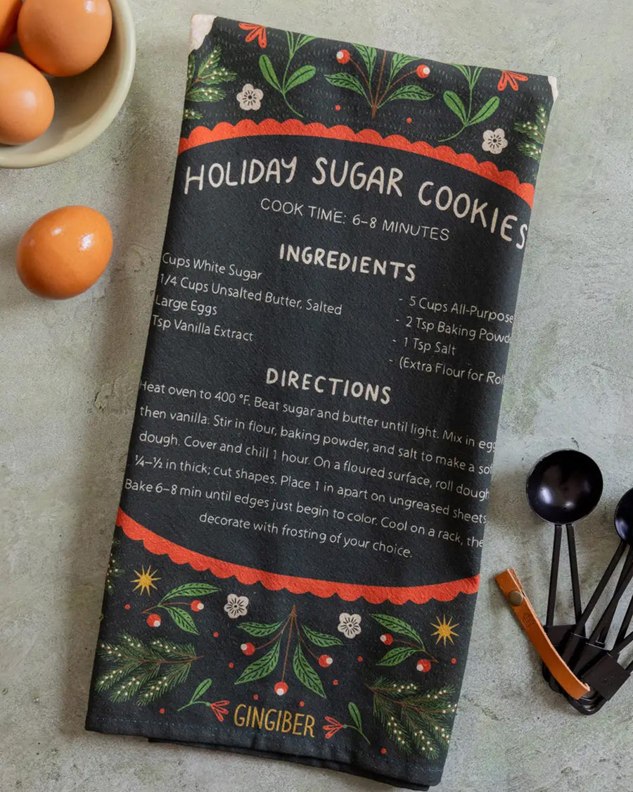 folded green tea towel with holiday sugar cookies with red floral and partridge print