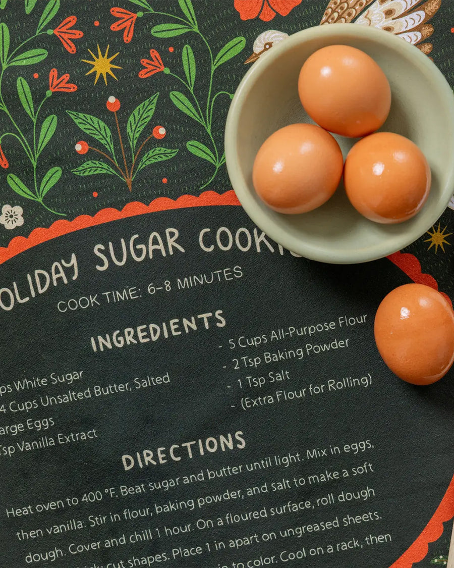 up close of green tea towel with holiday sugar cookies with red floral and partridge print