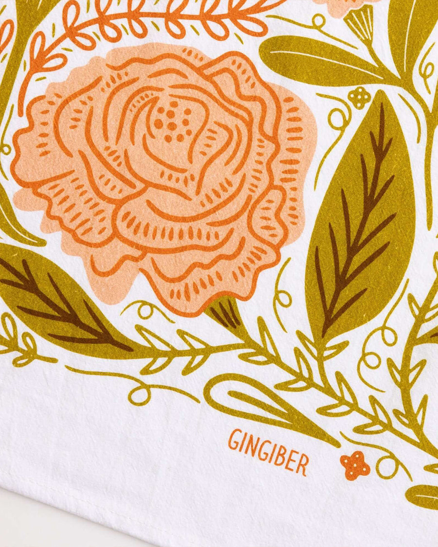 up close of white tea towel with pink butterfly moth print and green leaves