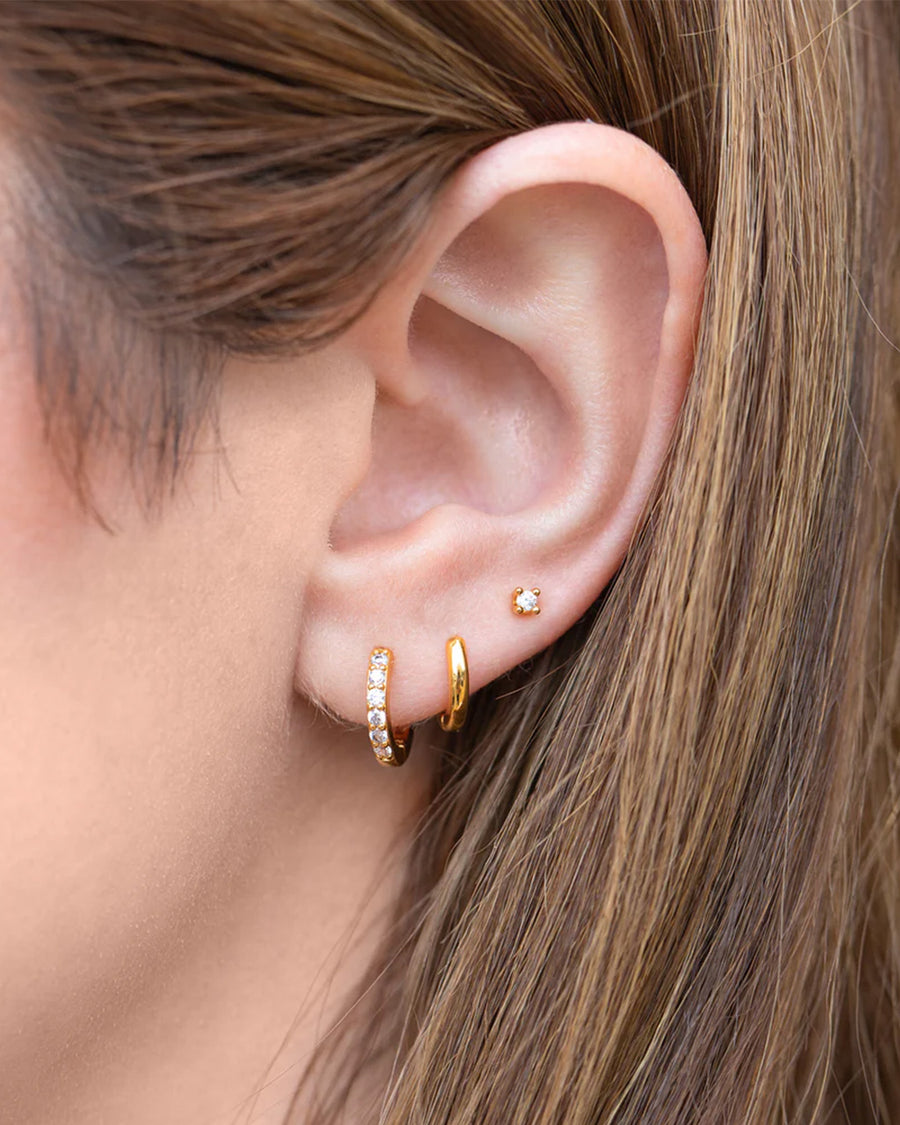 model wearing three pairs of gold essential earrings: gold hoops, crystal hoops and crystal studs